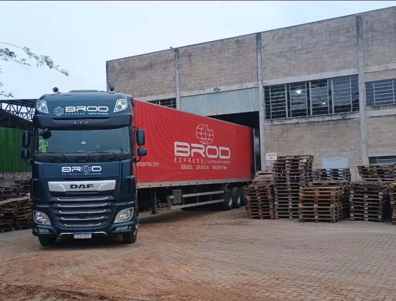 Carreta da Brod Express carregando em armazém, com o baú vermelho identificando a rota Brasil, Uruguai e Argentina