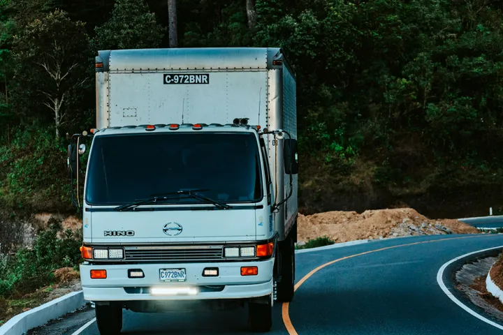 Caminhão baú em trecho de estrada, usado no transporte de alimentos